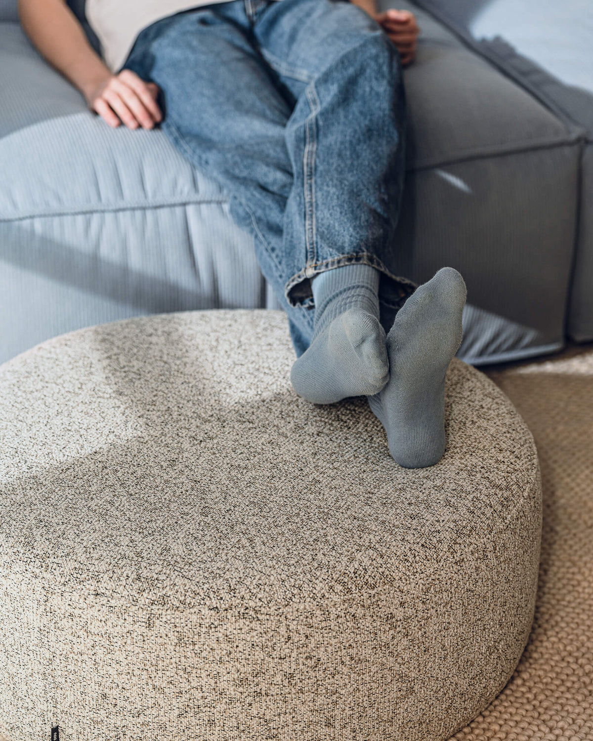 Bouclé pouf used as a comfortable footrest in the living room